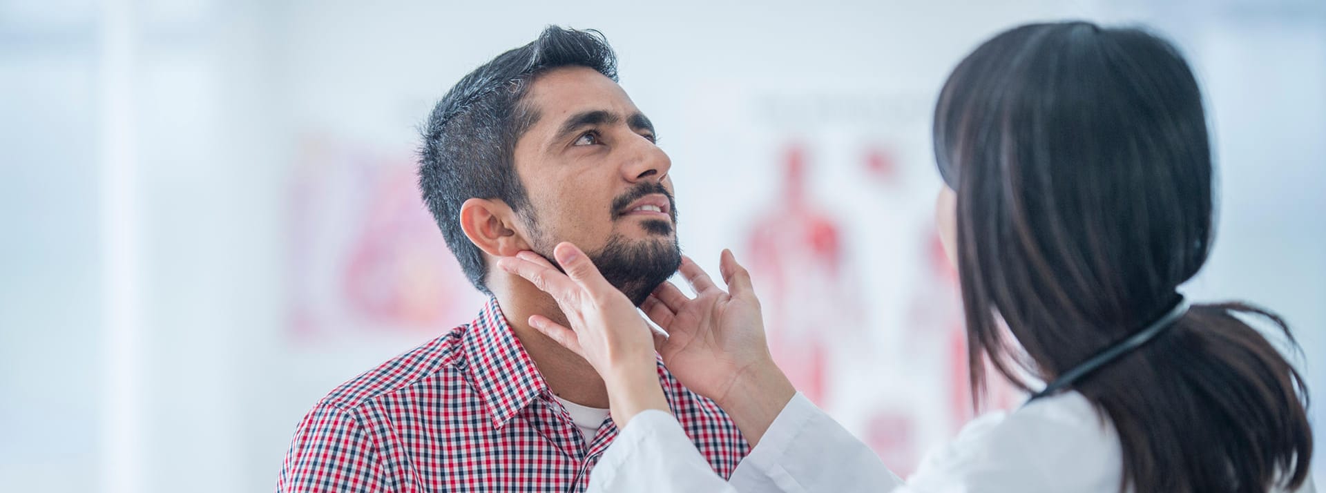 Ärztin untersucht die Lymphknoten am Hals eines Patienten.