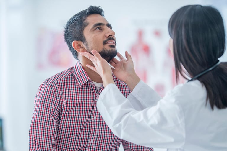 Ärztin untersucht die Lymphknoten am Hals eines Patienten.