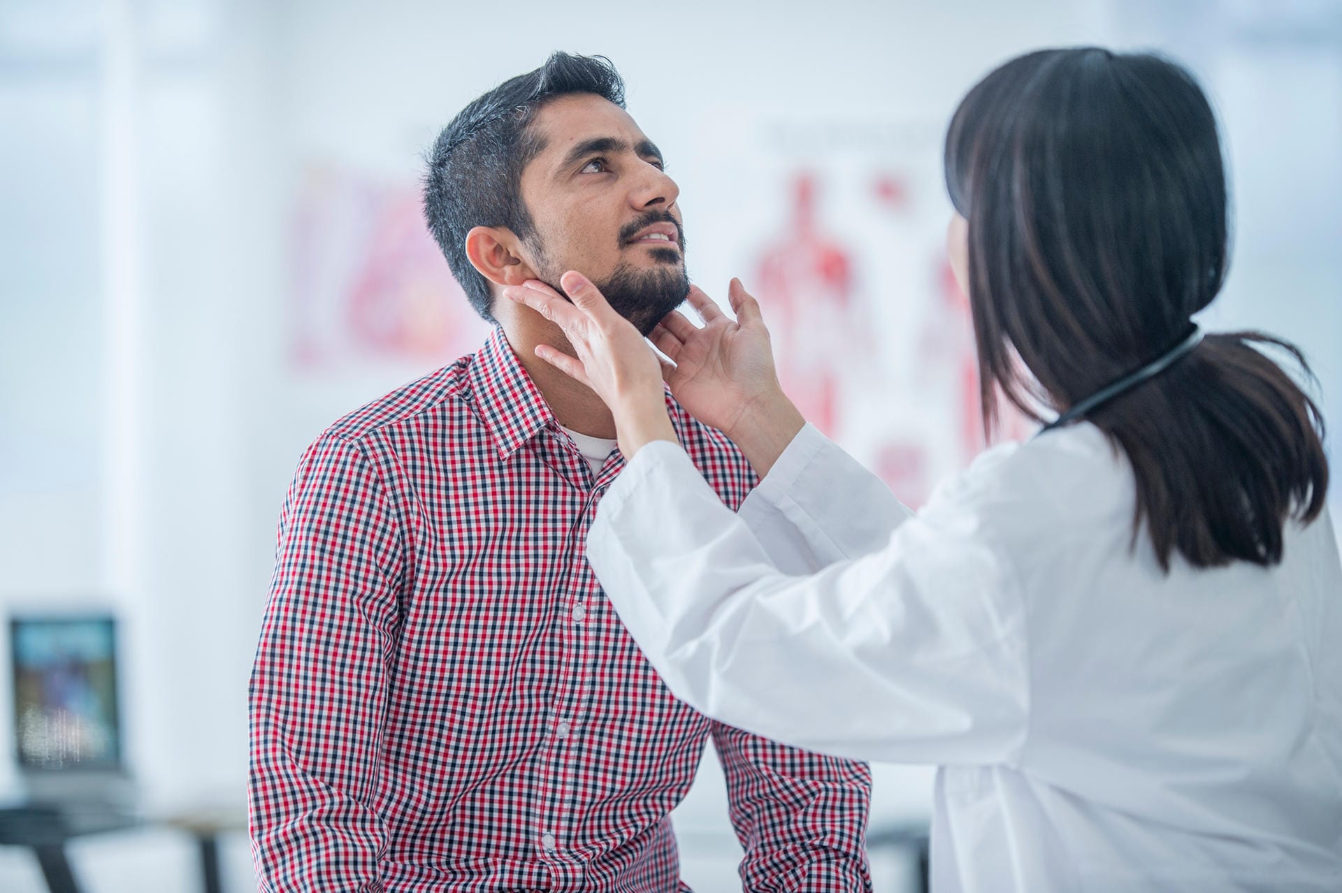 Ärztin untersucht die Lymphknoten am Hals eines Patienten.