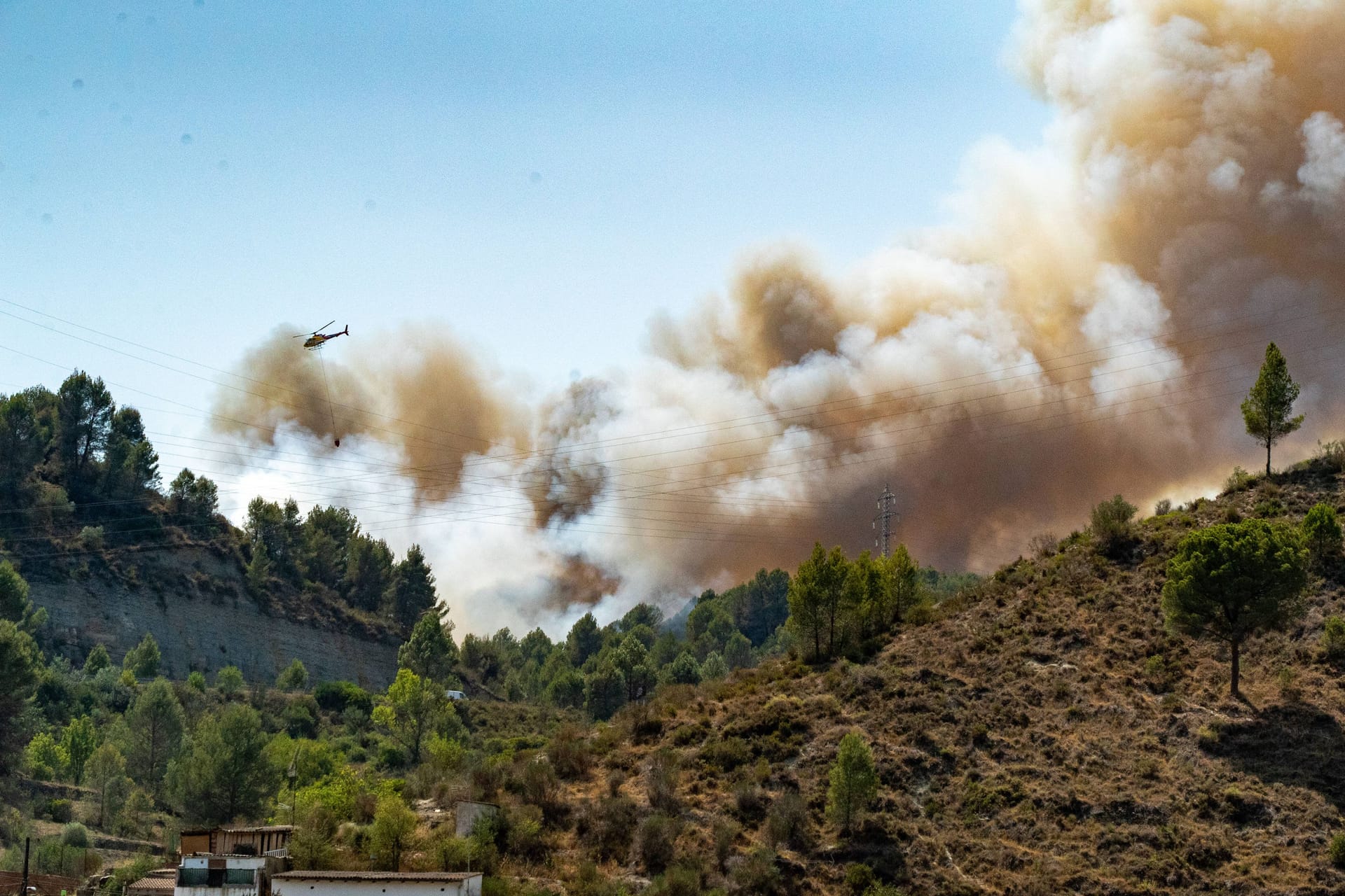 Ein Löschhubschrauber fliegt über ein brennendes Waldstück in Spanien (Archivbild): Nahe der bei Deutschen beliebten Costa Blanca Tausende Hektar in Flammen.