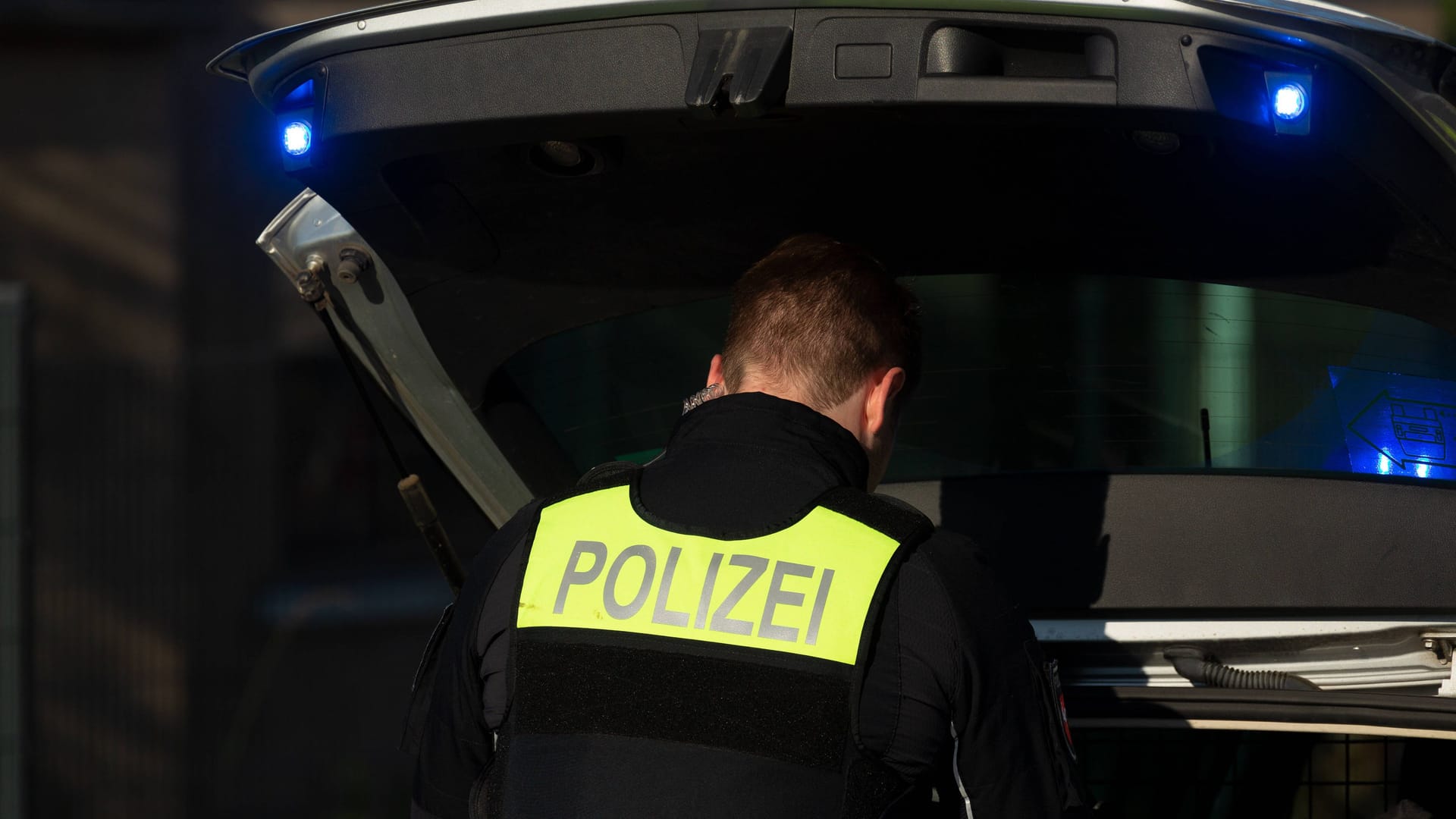 Ein Polizist steht vor einem Kofferraum (Symbolbild): Zeugen beobachteten, wie der Mann aus dem Kofferraum getragen wurde.