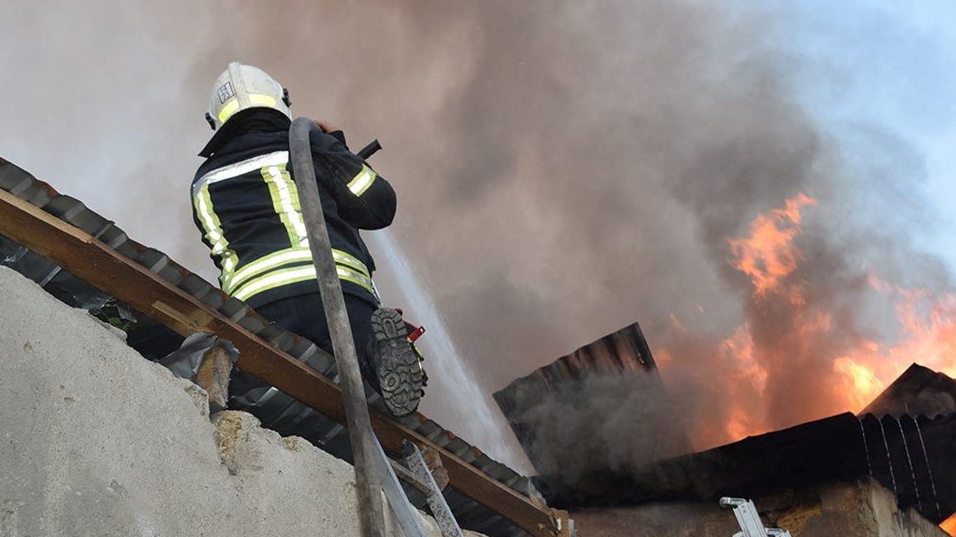 Ein Feuerwehrmann löscht einen Brand nach einem Raketenangriff in Mykolajiw: Auch in der Nacht wurde von Explosionen berichtet.