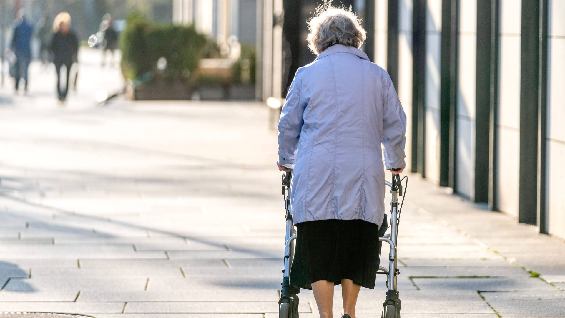 Eine alte Frau läuft durch eine Fussgängerzone in der Innenstadt von Dresden.