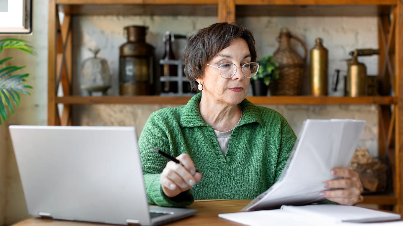 Eine ältere Frau prüft Dokumente (Symbolbild): Auch Rentner werden in Steuerklassen eingruppiert.