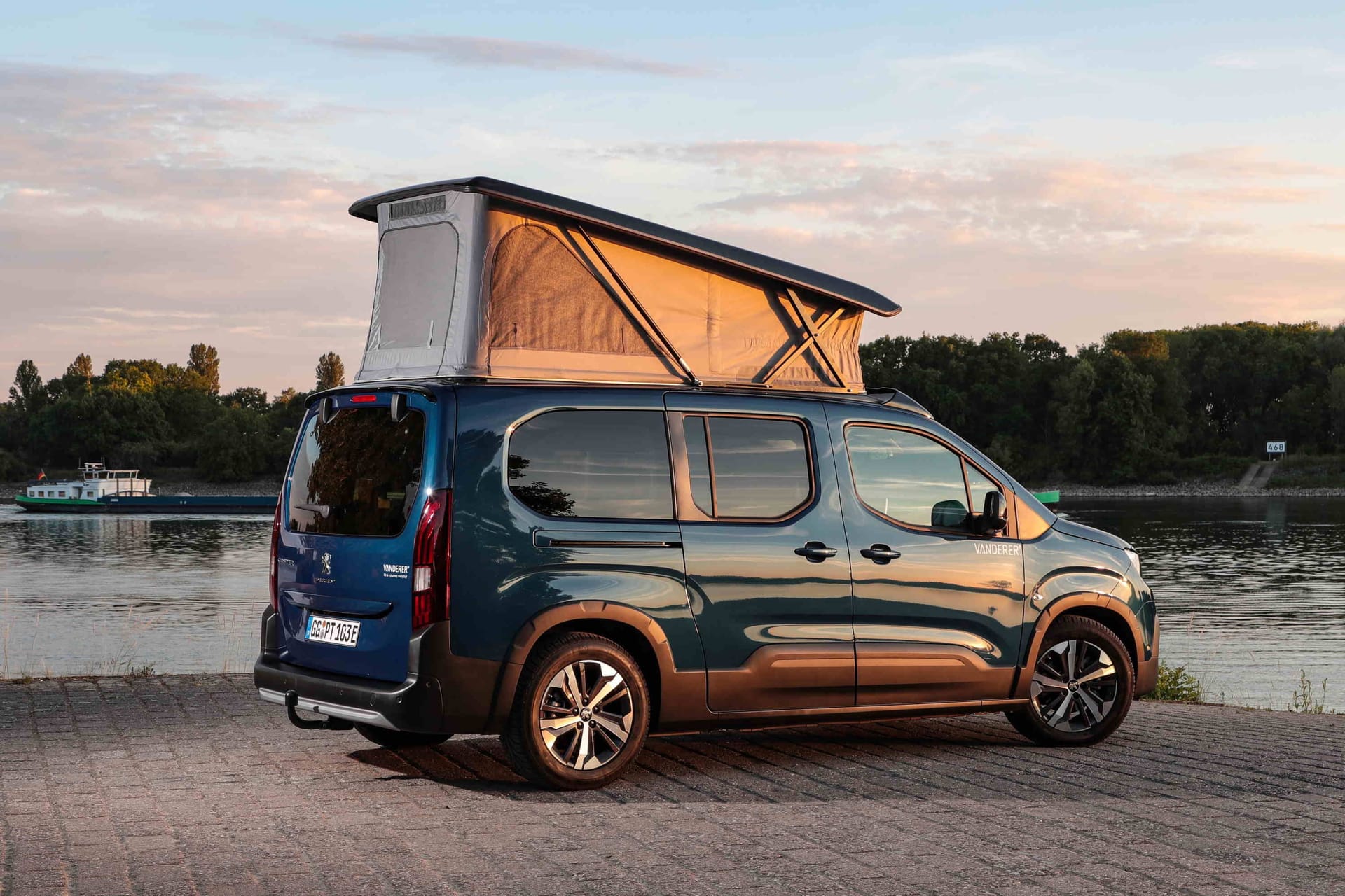 Die Firma Vanderer hat den Peugeot e-Rifter zum elektrisch angetriebenen Wohnmobil umgebaut. Das große Aufstelldach schafft sowohl Raum für Stehhöhe in Küche- und Wohnbereich als auch für ein weiteres Bett.