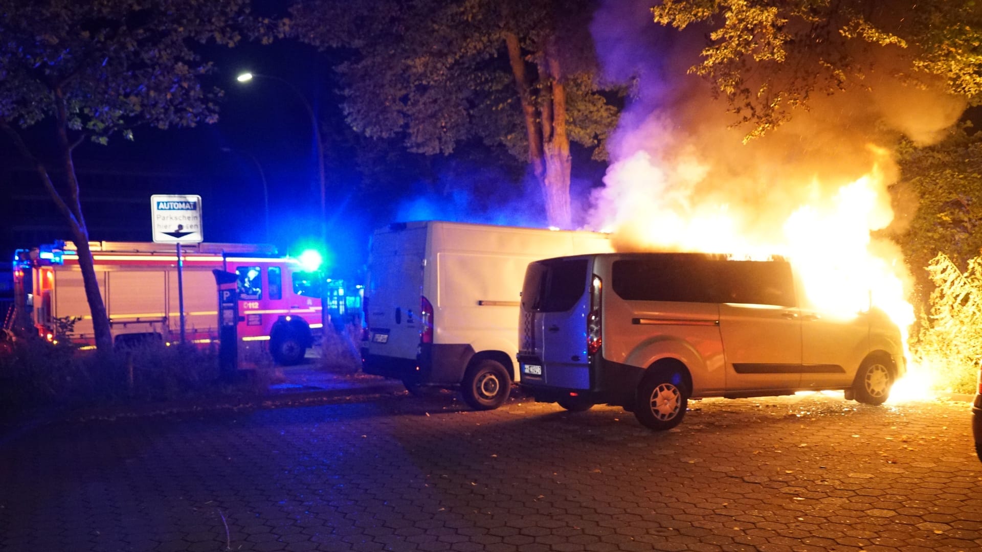 Ein Löschfahrzeug steht neben den brennenden Fahrzeugen.