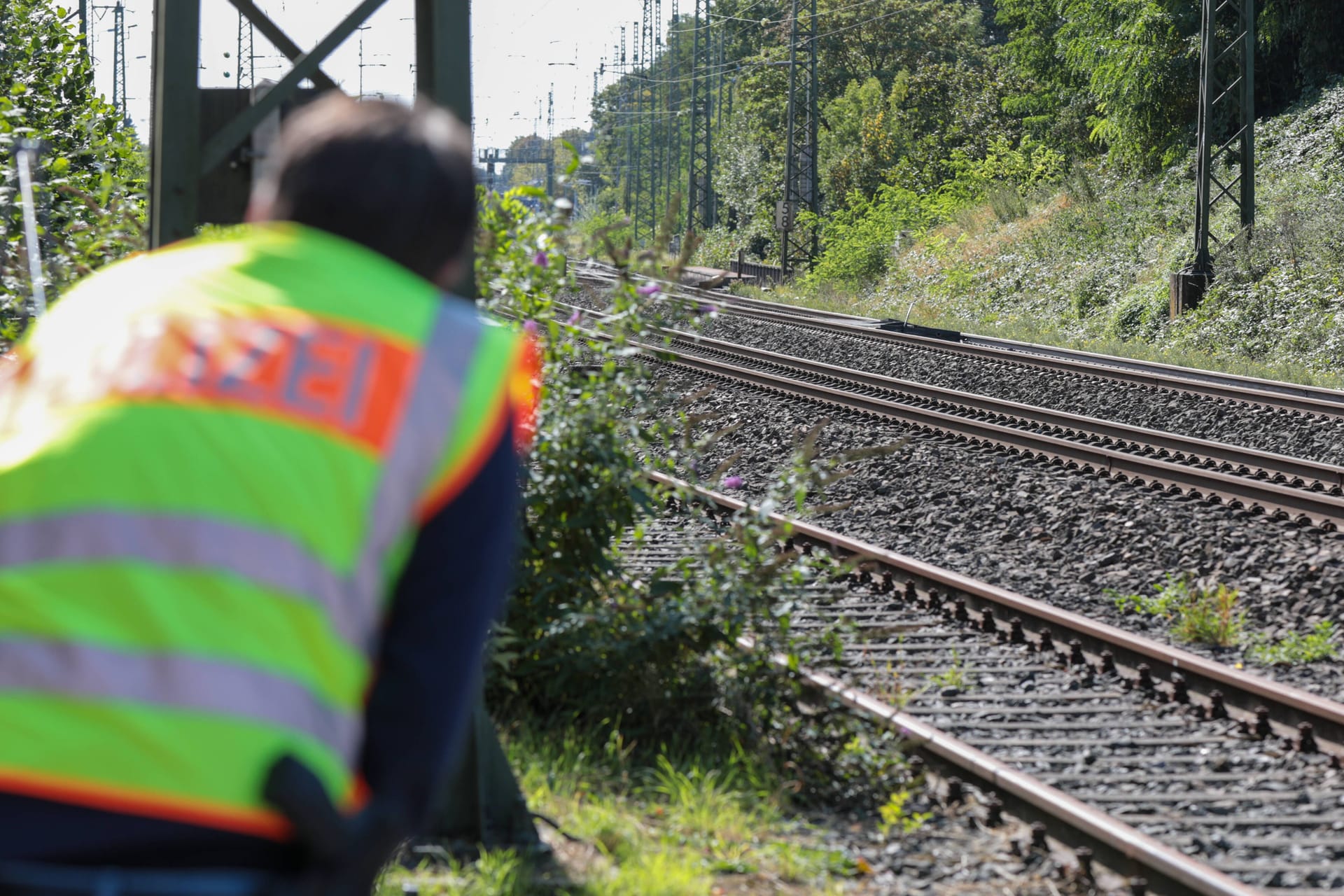 Ein Polizist blickt auf Bahnschienen (Symbolbild): Bei Kirchhain krachte ein Güterzug in einen führerlosen Traktor.