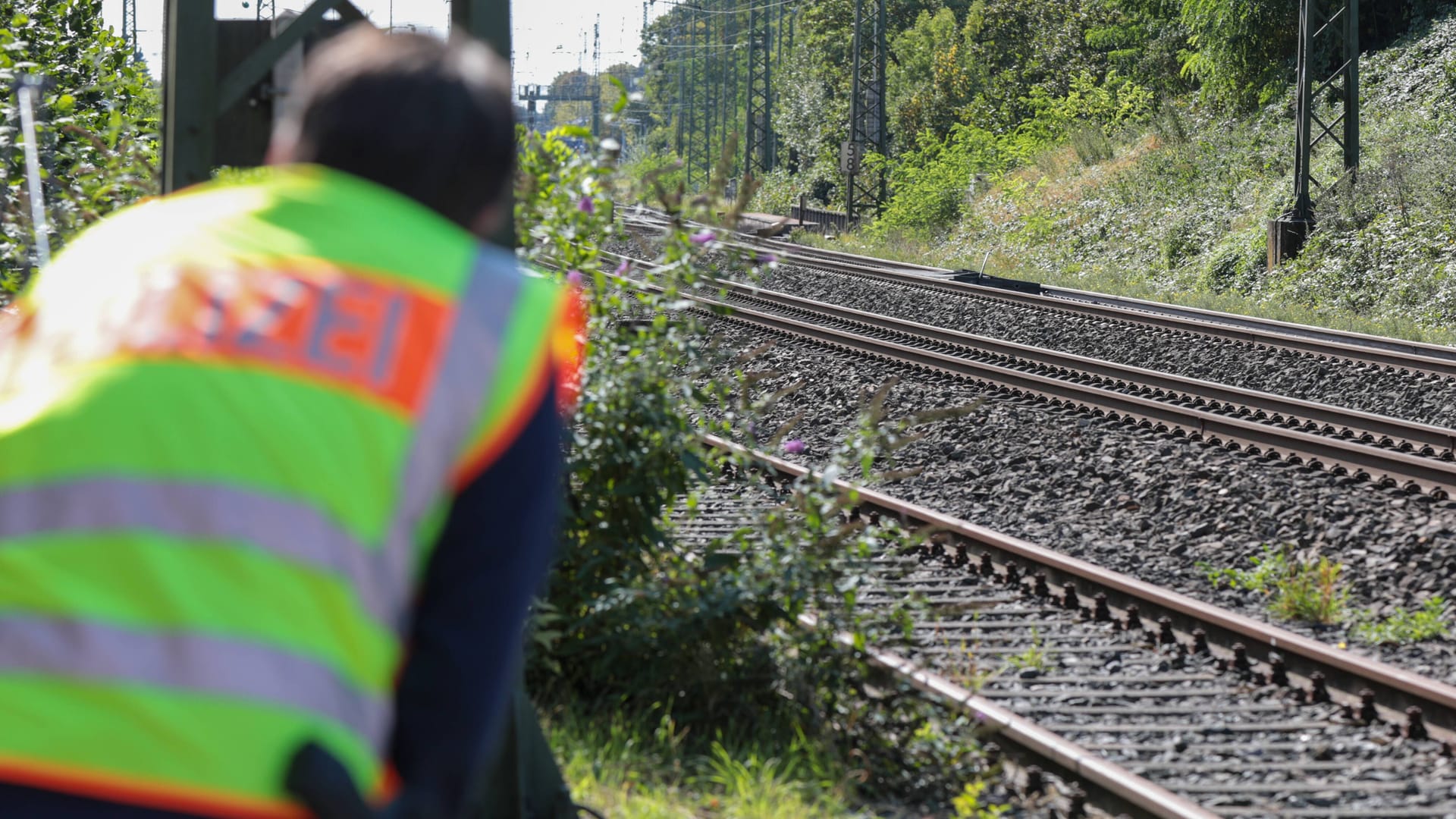 Ein Polizist blickt auf Bahnschienen (Symbolbild): Bei Kirchhain krachte ein Güterzug in einen führerlosen Traktor.