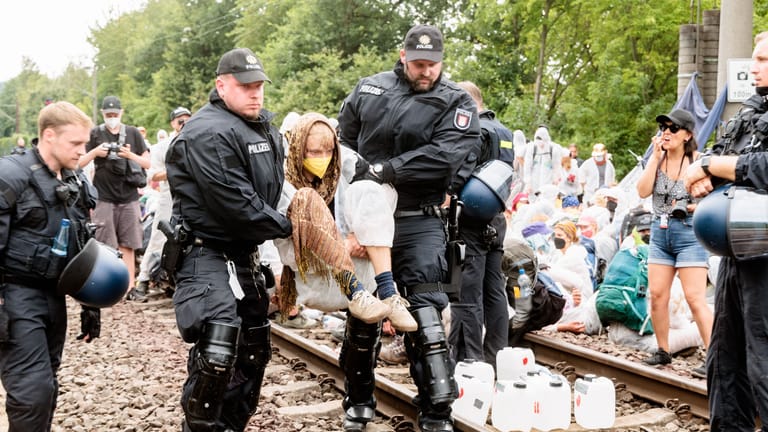 Polizisten tragen einen Klimaaktivisten in Hamburg von Bahngleisen.