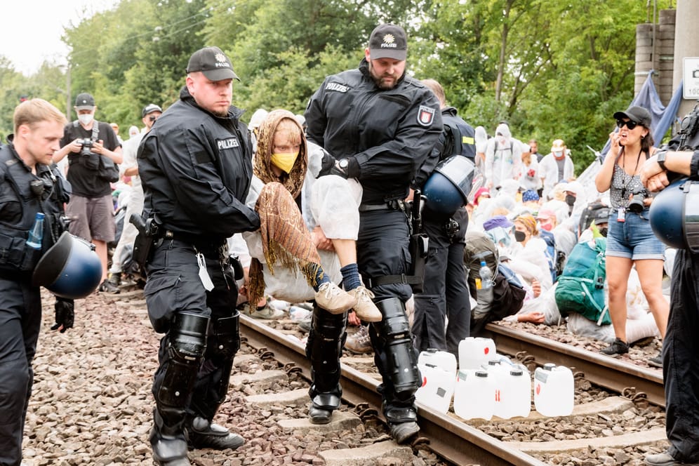 Polizisten tragen einen Klimaaktivisten in Hamburg von Bahngleisen.
