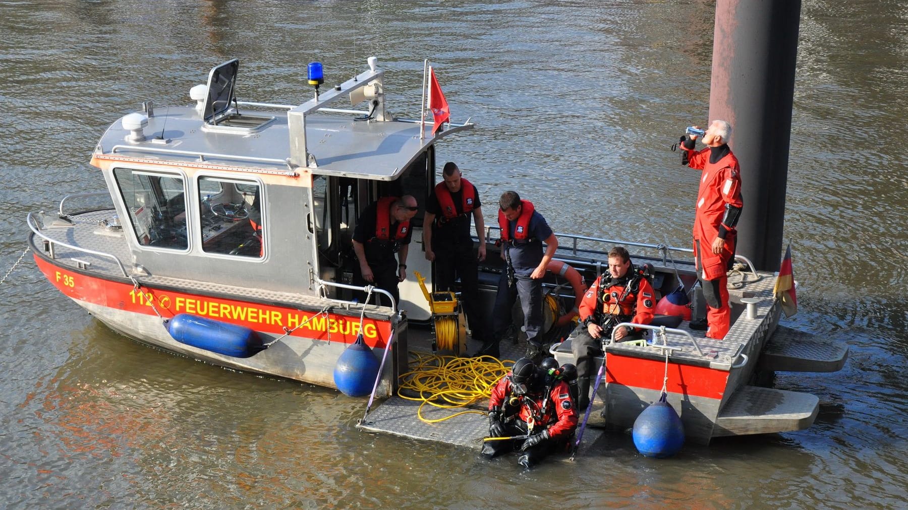 Taucher steigen ins Wasser der Elbe, um nach der Person zu suchen.