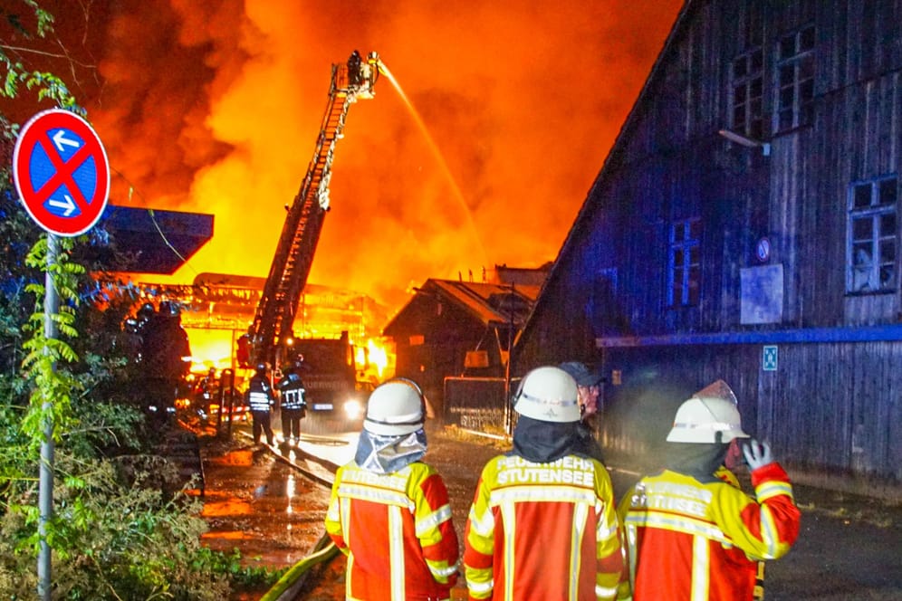 Baden-Württemberg, Weingarten: Einsatzkräfte der Feuerwehr löschen die brennende Lagerhalle.