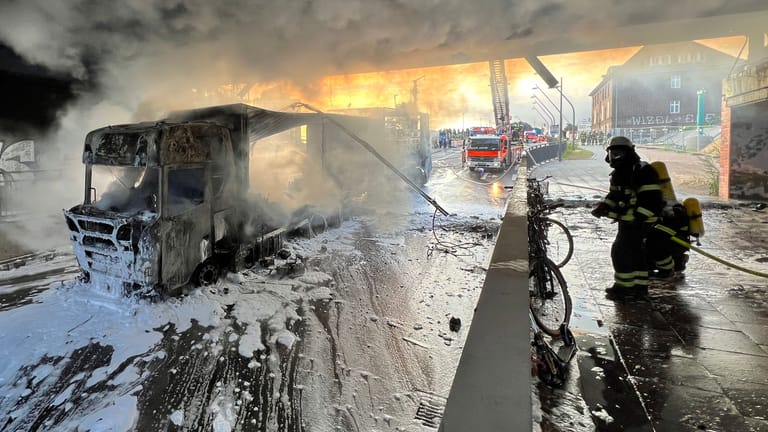 Feuerwehrleute löschen den brennenden Lkw unter einer Bahnbrücke: Wegen des Einsatzes am Morgen kam es zu Verzögerungen im Bahnverkehr.