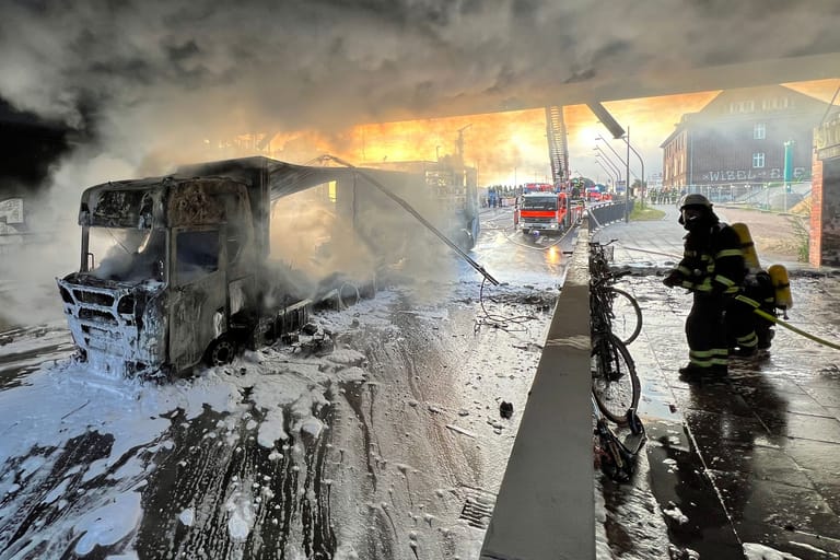 Feuerwehrleute löschen den brennenden Lkw unter einer Bahnbrücke: Wegen des Einsatzes am Morgen kam es zu Verzögerungen im Bahnverkehr.