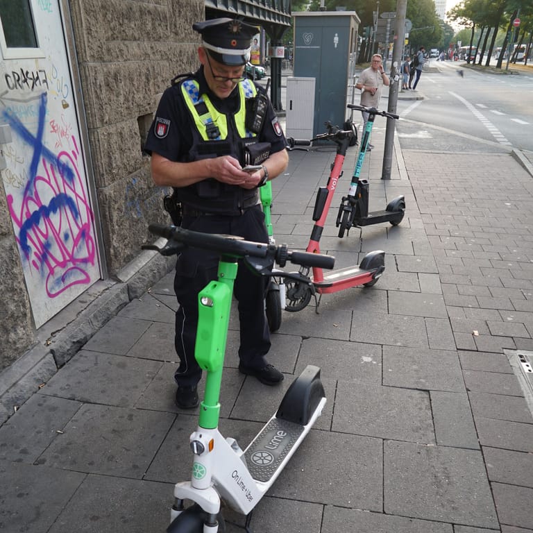 Ein Polizist neben mehreren E-Scootern auf dem Gehweg (Archivbild): Das soll nun ein Ende haben.
