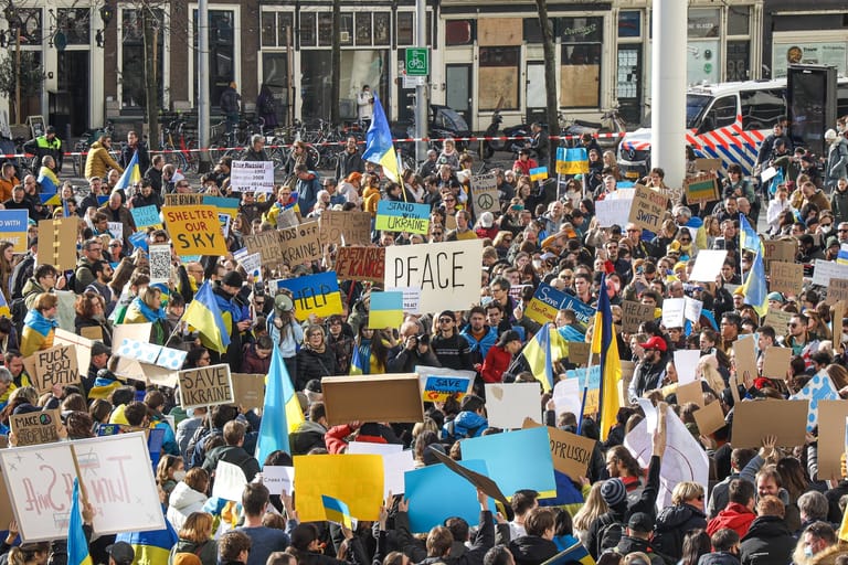 Weltweit gehen Hunderttausende Menschen, so wie hier im niederländischen Den Haag, gegen den Krieg auf die Straße und zeigen sich solidarisch mit der Ukraine. Die russische Armee beschießt unter anderem Stadtzentren. Zahlreiche Zivilistinnen und Zivilisten sterben bereits in den ersten Tagen nach der Invasion.