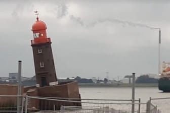 Ein Mann blickt auf die absackende Nordmole mit dem schiefen Leuchtturm in Bremerhaven: Hätte man dieses Desaster verhindern können?