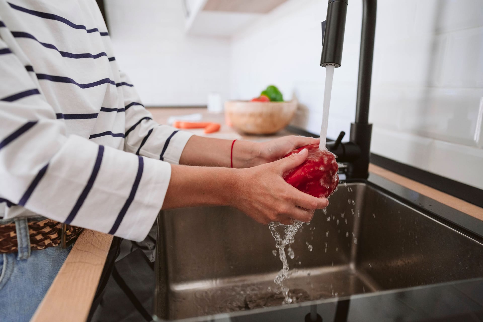 Eine Frau wäscht Gemüse (Symbolbild): 700 Haushalte bei Hannover müssen seit über einer Woche auf Trinkwasser aus der Leitung verzichten.