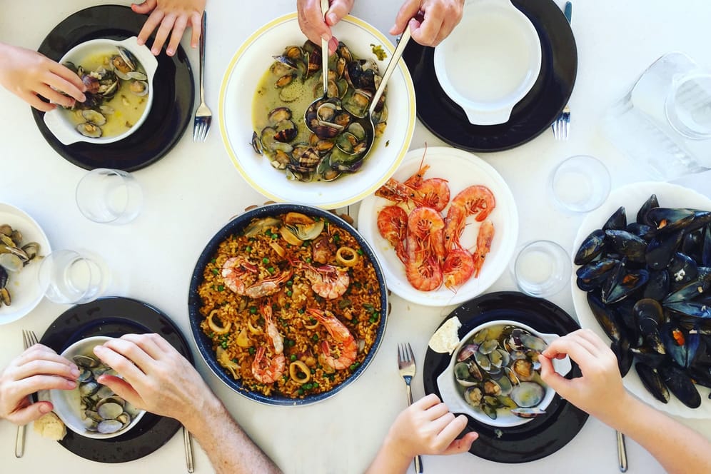 Vier Personen essen ein Gericht mit Meeresfrüchten.