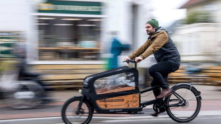 Ein Mann fährt mit einem Lastenrad durch die Stadt (Archiv): Große Kisten vor dem Lenker können die Wendigkeit der Räder beeinträchtigen.