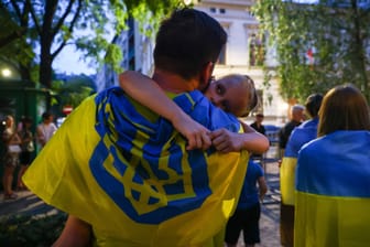 Vater mit Kind und ukrainischer Flagge (Symbolbild): Auch weiterhin erhalten Geflüchtete aus der Ukraine Asyl in Deutschland.