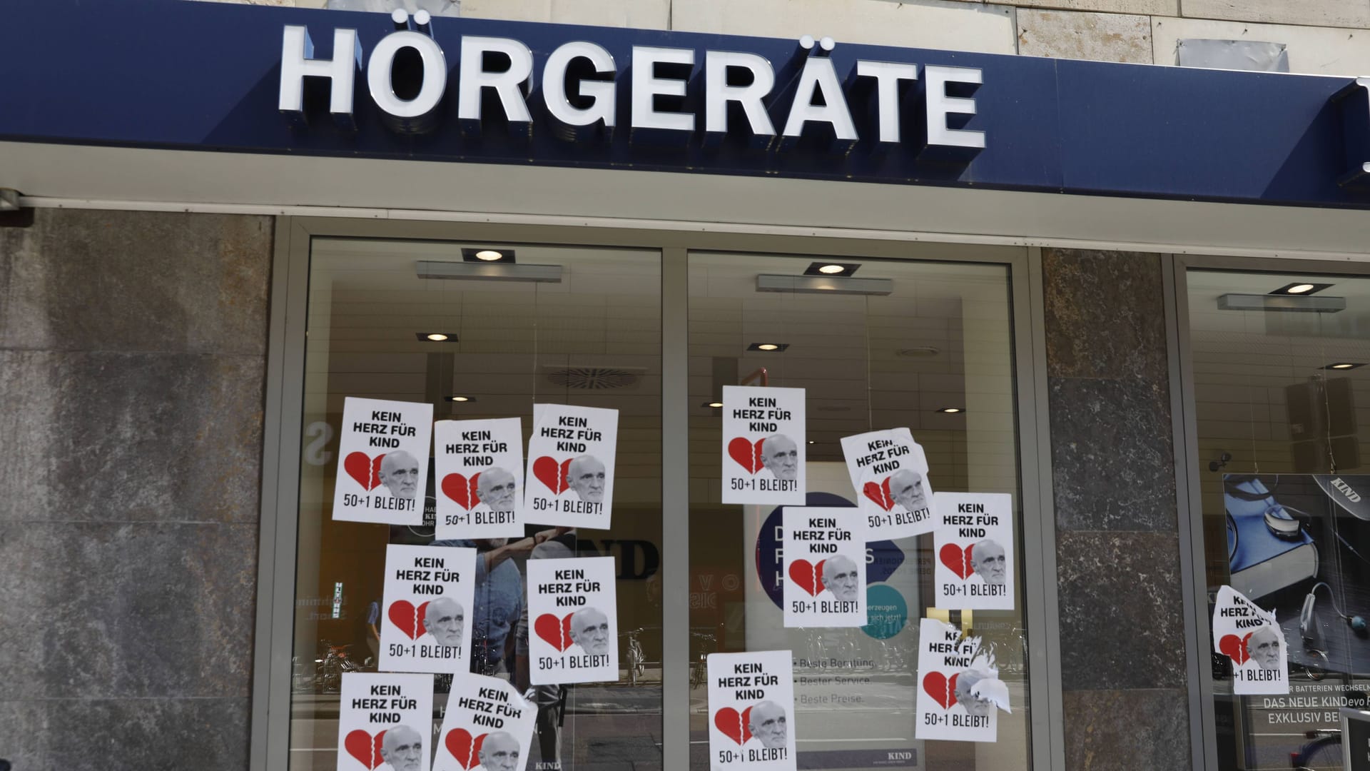 Protest an einem Schaufenster einer Filiale von Kind-Hörgeraete in Karlsruhe (Archivbild). Der Unternehmer ist Symbolfigur eines Kulturkampfes im deutschen Fußball.