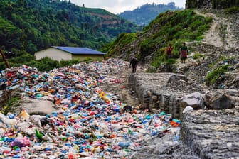 Menschen gehen entlang einer mit Müll gefüllten Straße: (Archivbild): In Nepals Hauptstadt bleibt derzeit aufgrund von Protesten tonnenweise Müll liegen.