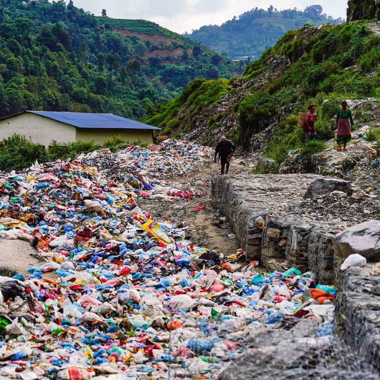 Menschen gehen entlang einer mit Müll gefüllten Straße: (Archivbild): In Nepals Hauptstadt bleibt derzeit aufgrund von Protesten tonnenweise Müll liegen.