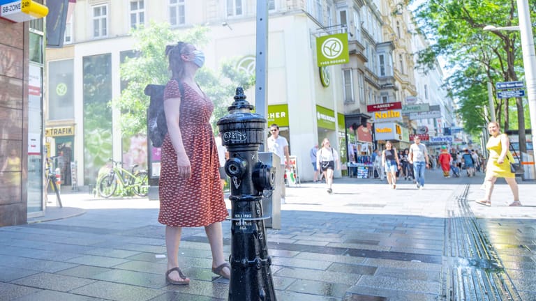 Kleine Abkühlung an einer Sprühnebelsäule in Wien: Straßen und Fassaden speichern tagsüber die Wärme und geben sie nachts wieder ab. Das macht Hitzewellen in Städten noch unerträglicher als im Umland.