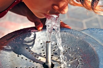 Ein kind erfrischt sich an einem Trinkbrunnen (Symbolbild): Überall in Deutschland sollen bald die kostenlosen Durstlöscher stehen.