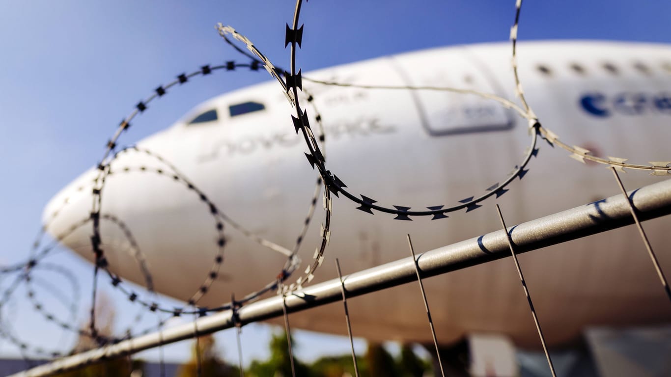 Flugzeug hinter Stacheldraht (Symbolfoto): Für den Verurteilten gibt es vorerst keine Einreisegenehmigung.