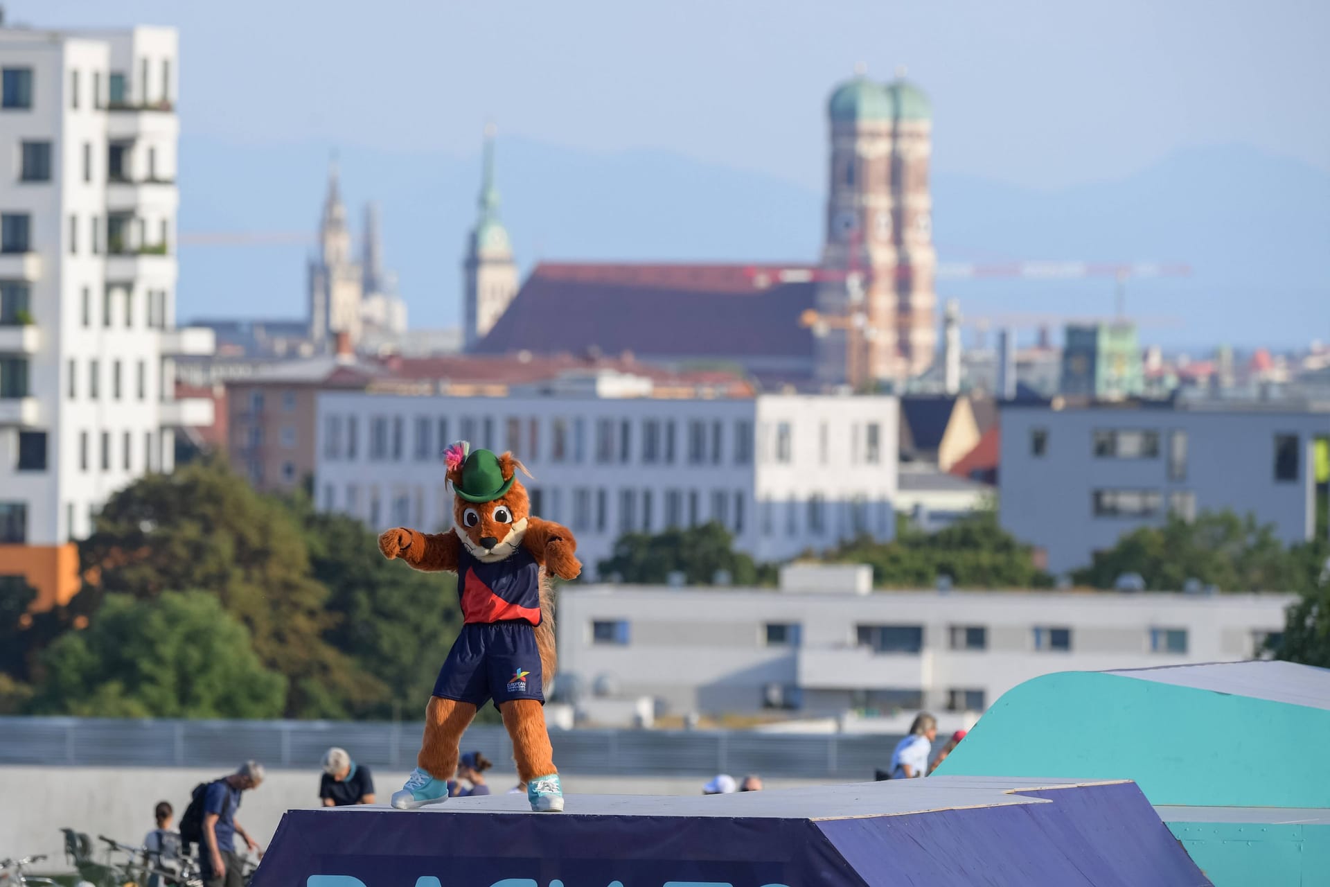 Olympiaberg in München, im Hintergrund die Frauenkirche: Im Vordergrund das Maskottchen der EM, das Eichhörnchen "Gfrei Di!", also "Freu' Dich!"