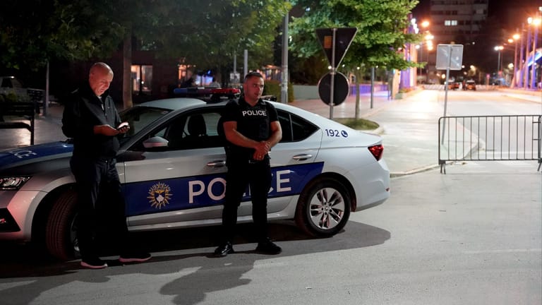 Polizisten sind in an einer Absperrung in Mitrovica im Einsatz während in der Stadt Sirenenalarm zu hören ist.