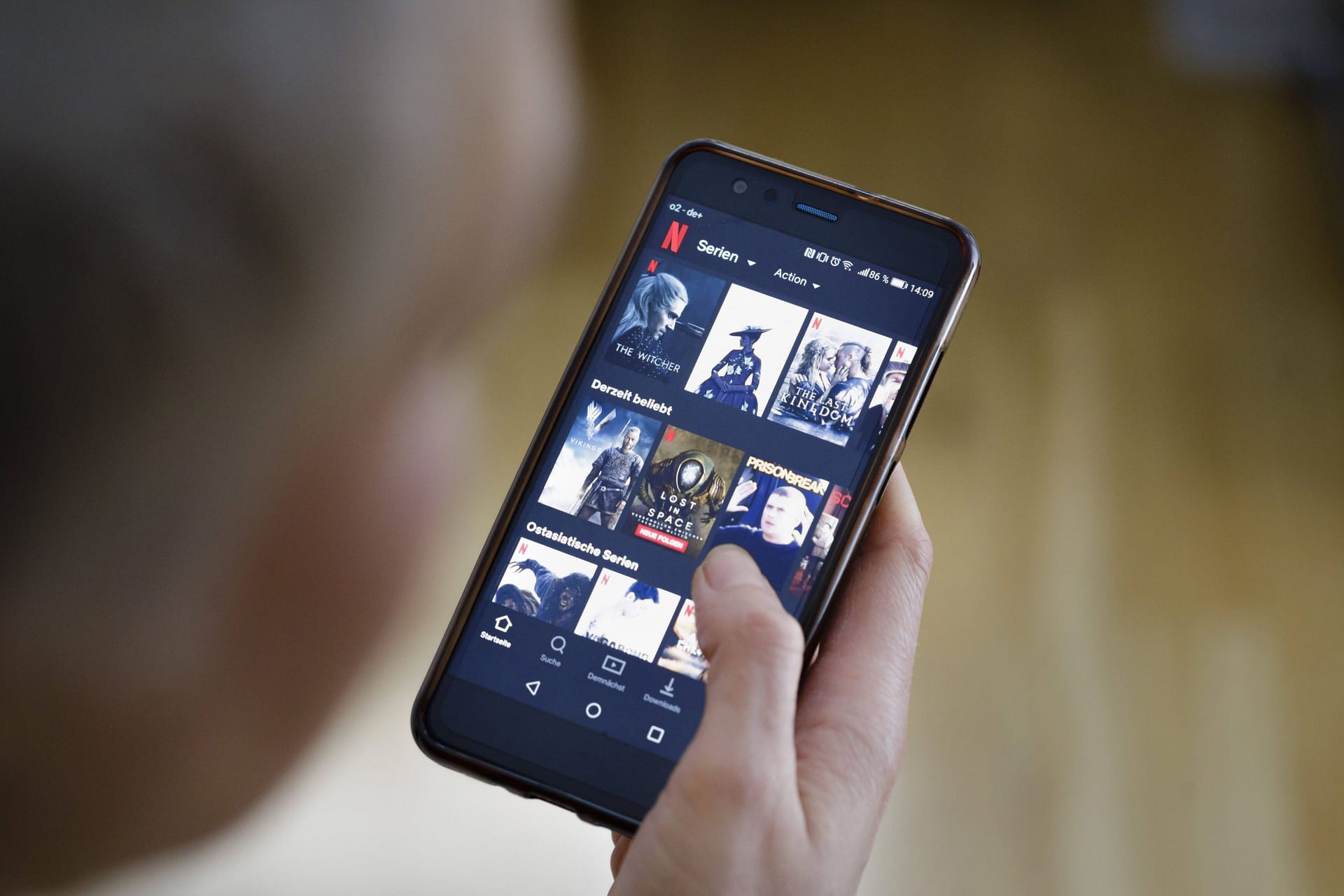 Eine Frau schaut auf ihrem Smartphone die App von NETFLIX an