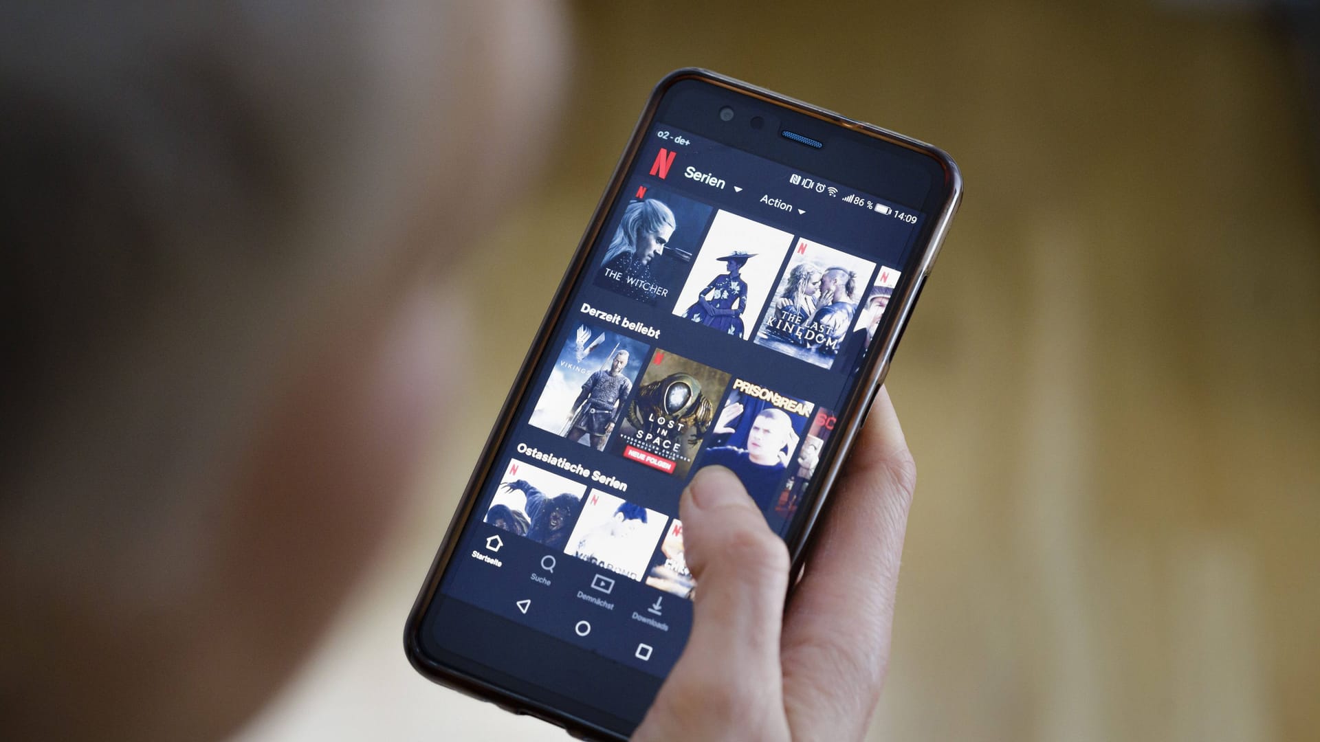 Eine Frau schaut auf ihrem Smartphone die App von NETFLIX an