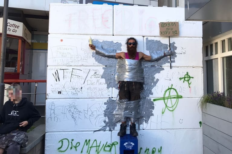 Ein Mann wurde mit Klebebank an eine Mauer in Westerland geklebt: Die Punks wollen mit der Aktion Kritik an der baulichen Maßnahme der Gemeinde üben.