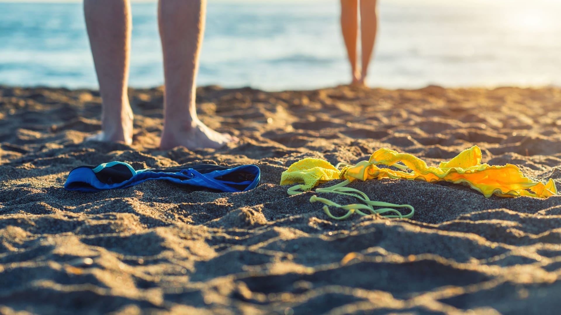 Frauen- und Männerfüße im Sand