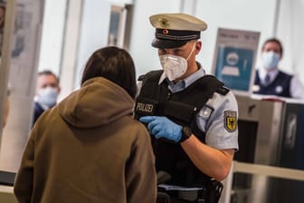 Ein Bundespolizist überprüft eine Reisende (Symbolbild): Am Sonntag kam es im Münchner Flughafen zu einem Polizeieinsatz.