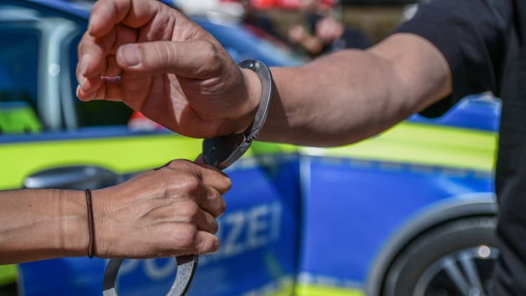 Ein Polizeibeamter legt einer Person Handschellen an (Symbolbild): In Hamburg ist ein 60-Jähriger angegriffen worden.
