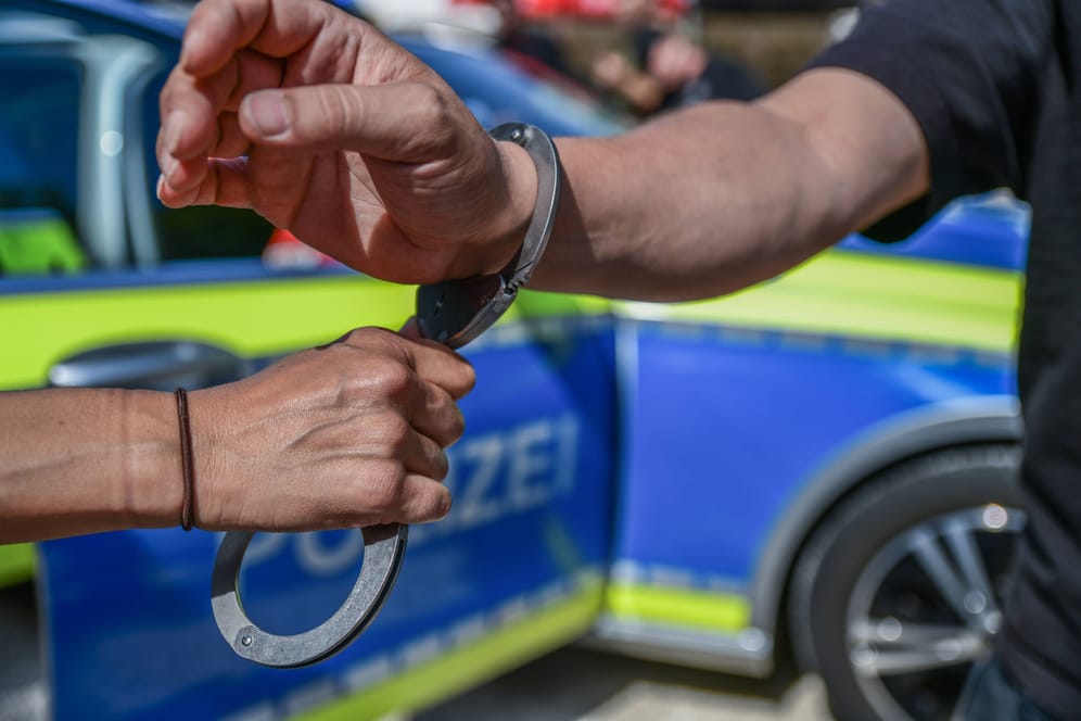 Ein Polizeibeamter legt einer Person Handschellen an (Symbolbild): In Hamburg ist ein 60-Jähriger angegriffen worden.