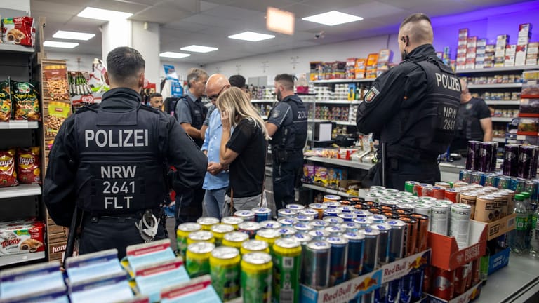 Beamte von Polizei und Zoll durchsuchen bei einer Razzia im Duisburger Norden am Freitagabend einen Kiosk: 13 Objekte und 130 Personen wurden insgesamt kontrolliert.