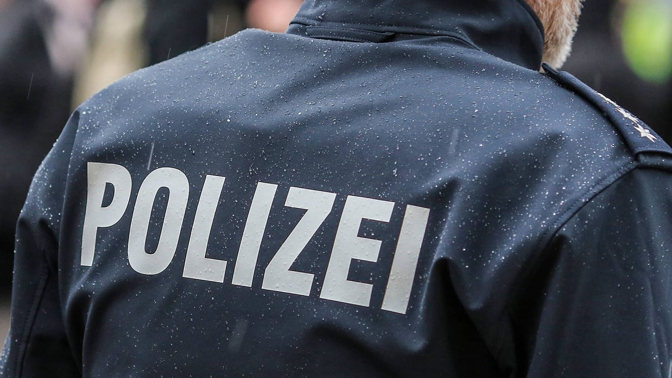 Polizist in Nahaufnahme mit Schutzweste und Schriftzug (Symbolfoto): Die Gruppe floh, die Beamten suchen Zeugen.