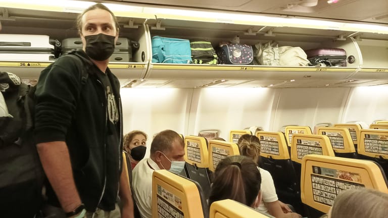 Fluggäste in einem Flieger mit Maske: Diese Regel soll nun offenbar gestrichen werden.