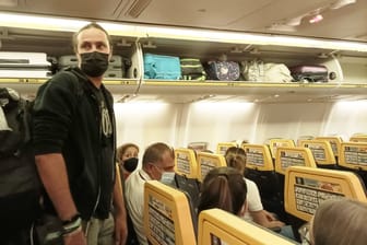 Fluggäste in einem Flieger mit Maske: Diese Regel soll nun offenbar gestrichen werden.