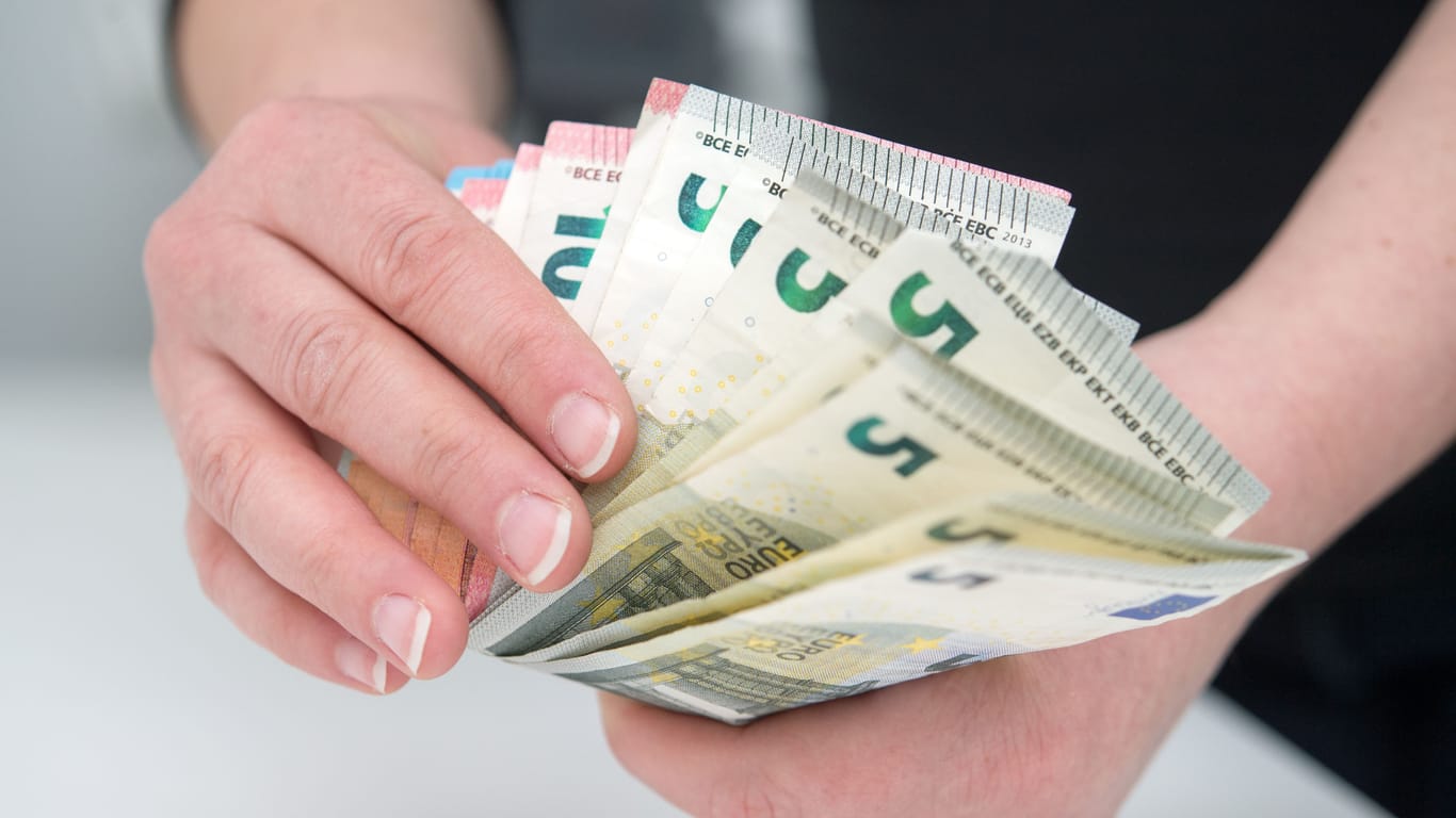 Ein Mann hält Geldscheine in der Hand (Symbolbild): Dividenden vergrößern Ihren Erfolg bei der Geldanlage.