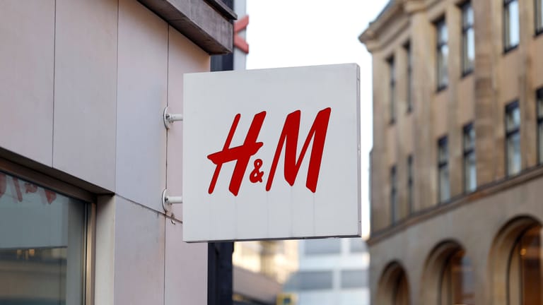 Firmenlogo von H&M an einer Filiale: Inflation und zögernde Kundinnen und Kunden machen der schwedischen Modekette H&M derzeit zu schaffen.