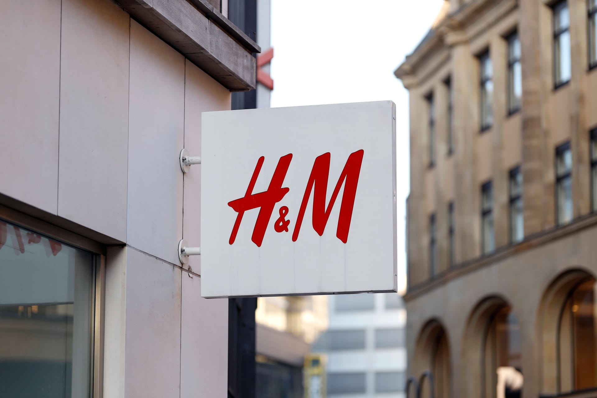 Firmenlogo von H&M an einer Filiale: Inflation und zögernde Kundinnen und Kunden machen der schwedischen Modekette H&M derzeit zu schaffen.