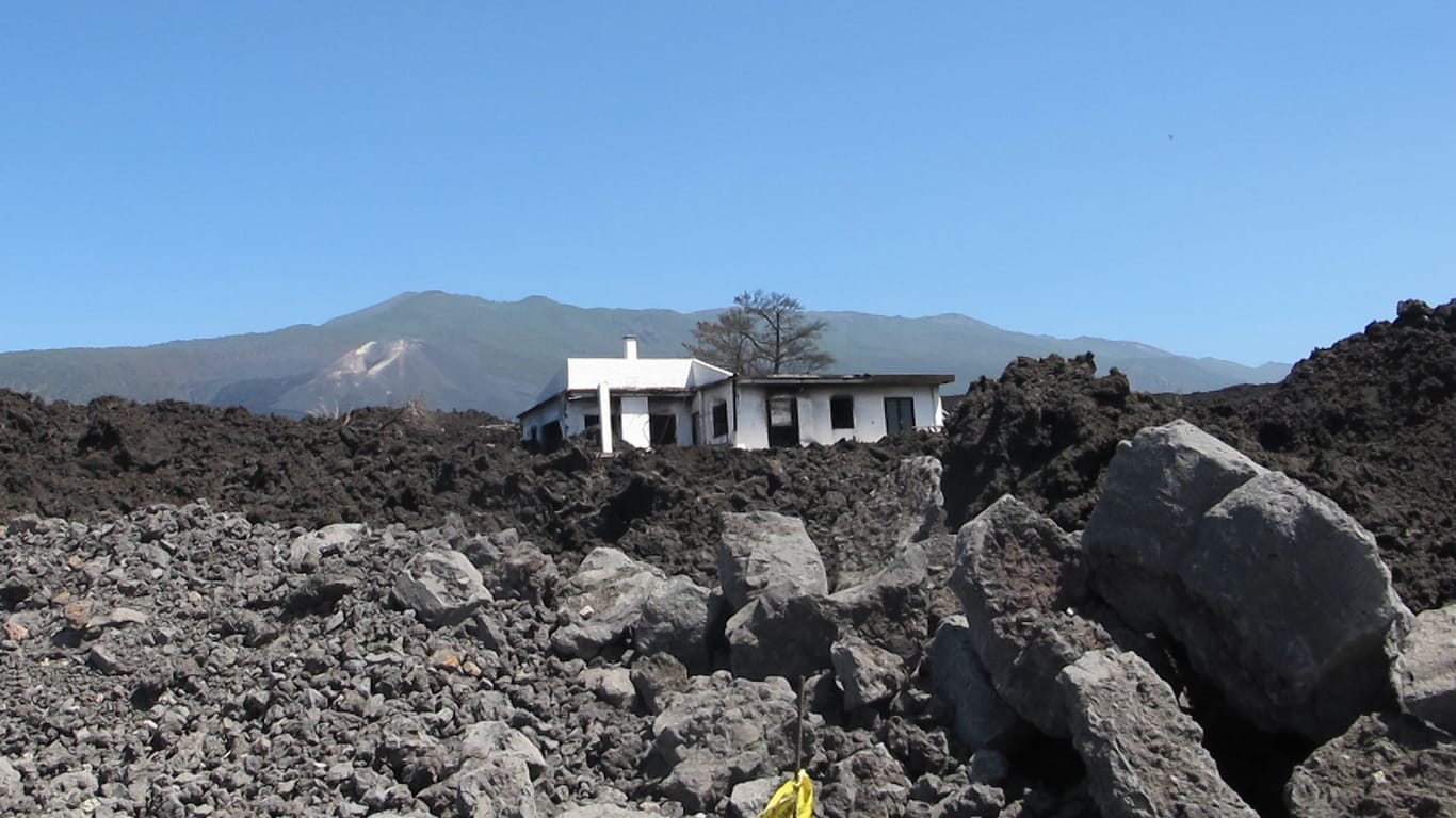 Ein beschädigtes Wohnhaus in der erkalteten Lava auf La Palma: Auch ein Jahr nach dem Vulkanausbruch hat die Urlaubsinsel noch viele Probleme.