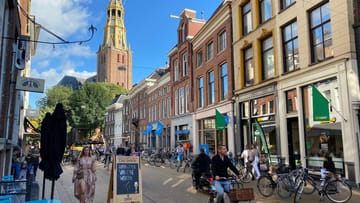 Old Town Groningen: Een winkelstraat in het centrum van Groningen, met op de achtergrond de toren van de der R. kerk.