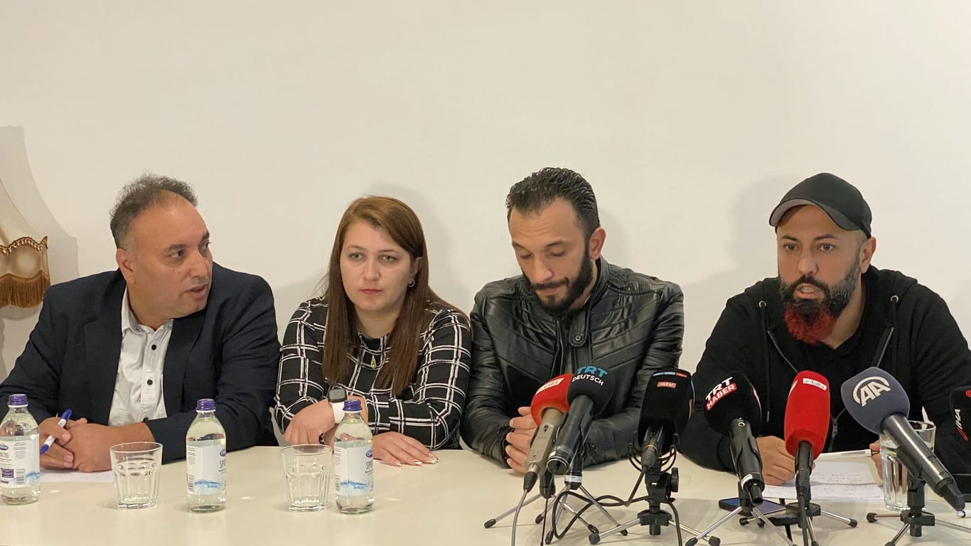 Ferat Kocak (r, Die Linke) sitzt neben einem Ehepaar aus Syrien und dessen Dolmetscher (l) bei einer Pressekonferenz der Linkspartei.